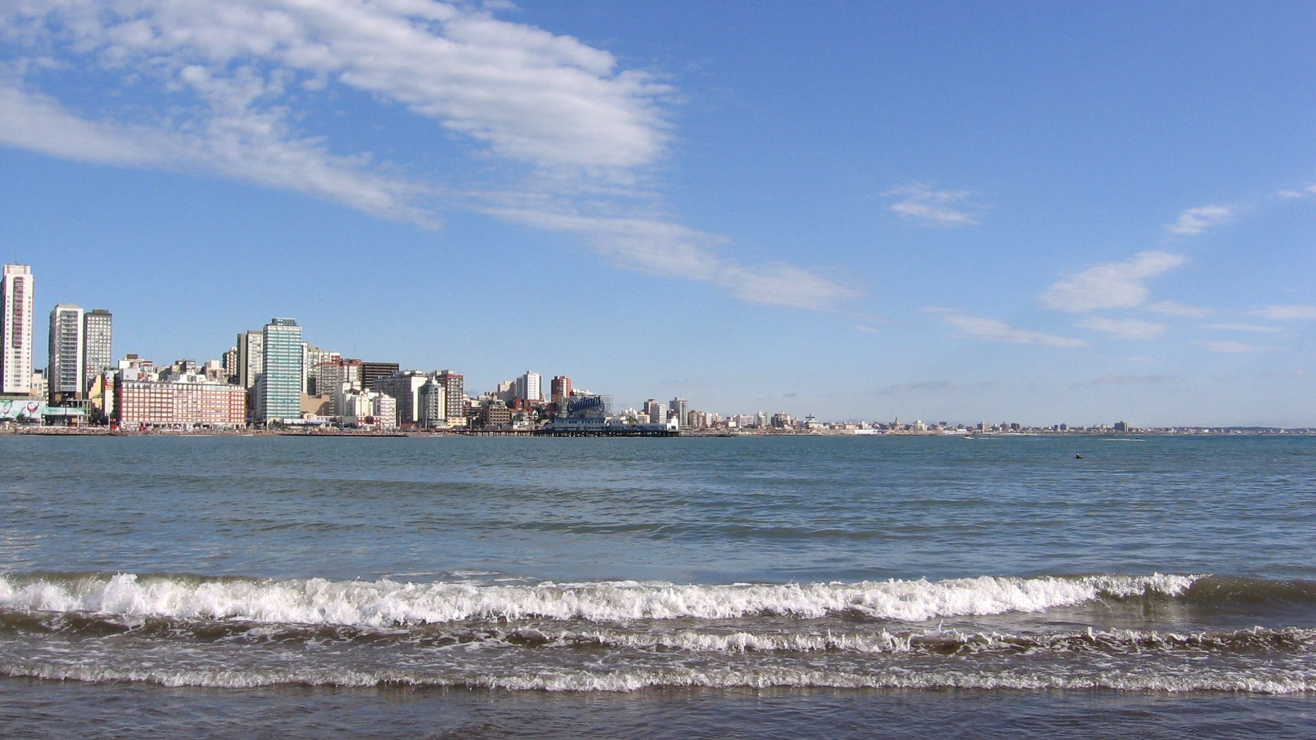 Playa en Mar del Plata cerca de los departamentos, con arena blanca y el océano Atlántico de fondo.